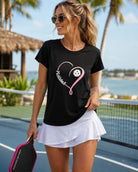 Women's black poly-spandex crew neck tee featuring a pink heart pickleball graphic, styled for casual resort-chic and pickleball-inspired fashion