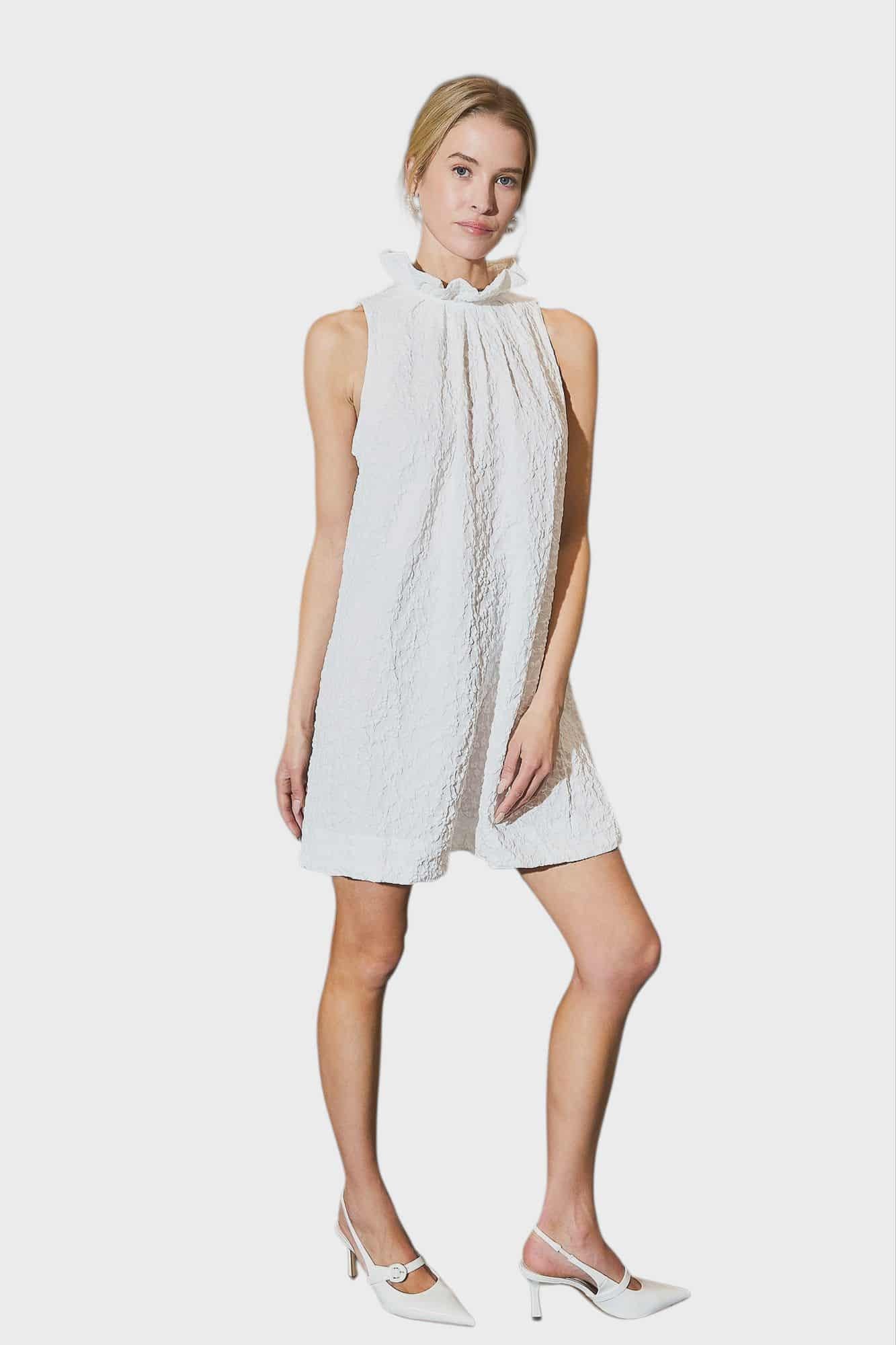 Woman wearing a white sleeveless dress with a high neckline on a white background