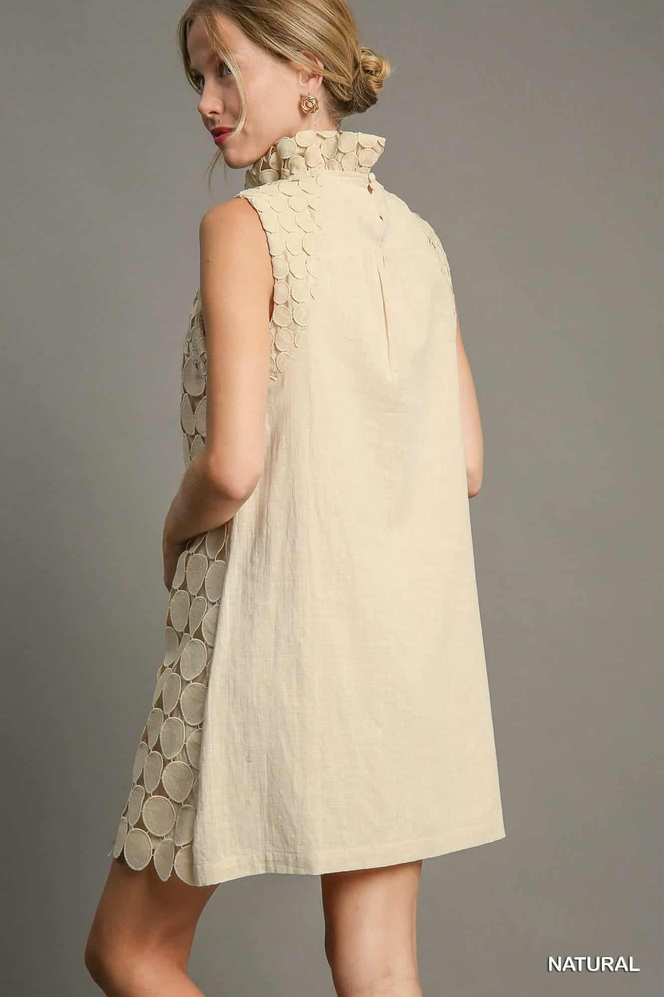 Woman wearing a beige sleeveless dress with a textured back on a gray background, back view