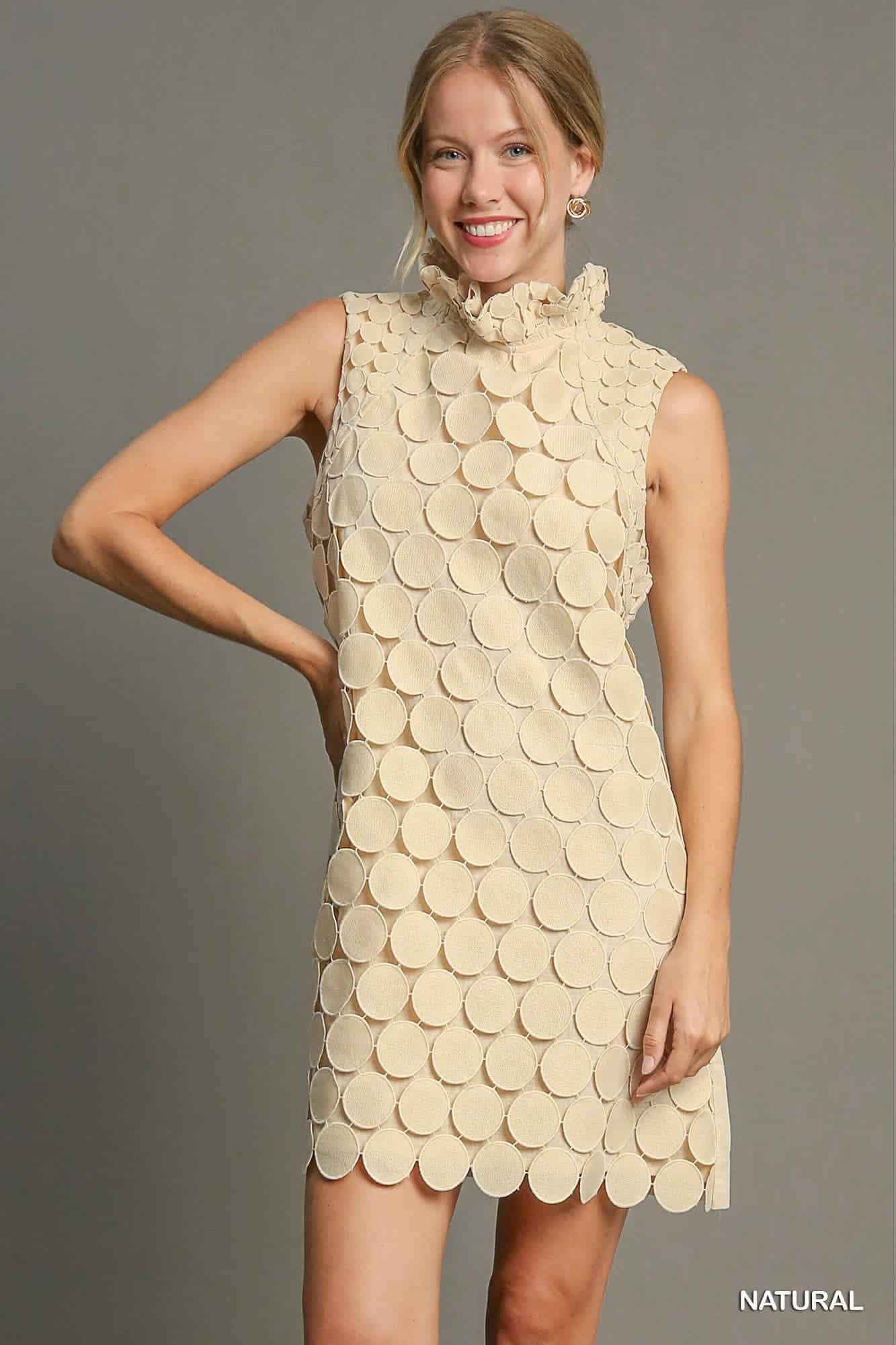 . Close-up of circular textured fabric and ruffled neckline on natural shift dress.