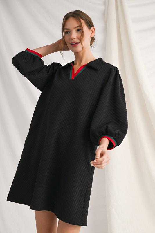 . Model wearing black textured shift dress with puff sleeves