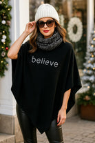 Woman wearing a black lightweight poncho with the word “believe” in rhinestones, styled for the winter holidays with a knit beanie and leather leggings.