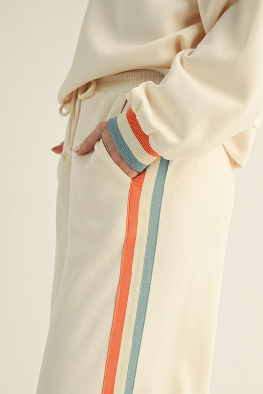 Close-up of a beige sweatshirt with colorful stripes on a neutral background