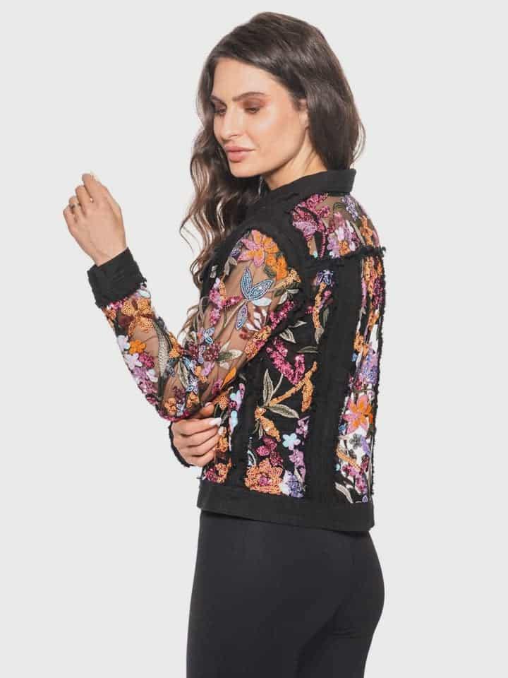 Woman wearing a black jacket with colorful floral pattern made of  sequins and embroidery on a white background