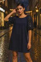  Chic woman wearing navy dress with sequin floral puff sleeves on city street
