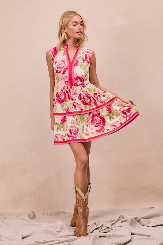 Woman wearing a floral dress with pink accents and cowboy boots on a beige background