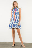 Woman wearing a sleeveless dress with blue floral pattern on a white background