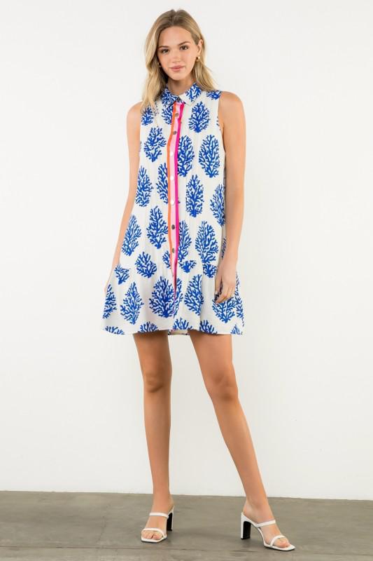 Woman wearing a sleeveless dress with blue floral pattern on a white background