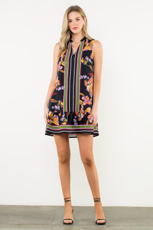 Woman wearing a sleeveless dress with floral and striped pattern on a white background