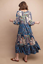 Woman wearing a long, patterned dress against a beige background