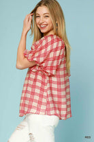 Woman wearing a red and white checkered blouse against a light blue background, Sideview