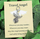 Silver angel charm on a 'Travel Angel' card with green leaves in the background