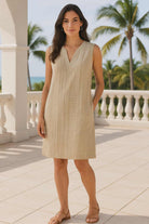 Woman in a LIGHT SAGE dress standing on a balcony with palm trees in the background