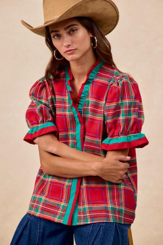 Woman wearing red plaid blouse with green trim and ruffled puff sleeves – festive holiday top by Petunias of Naples