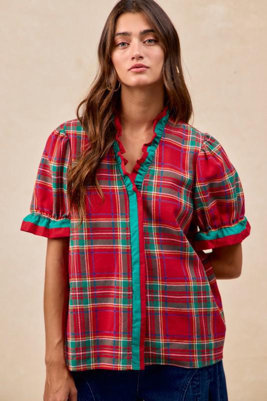 Woman wearing red plaid blouse with green trim and ruffled puff sleeves – festive holiday top by Petunias of Naples