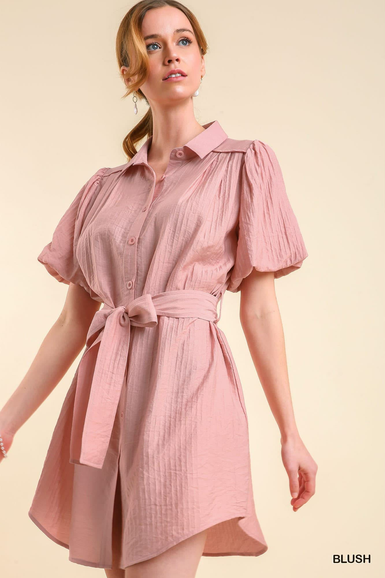 Woman wearing a pink dress with puff sleeves on a beige background