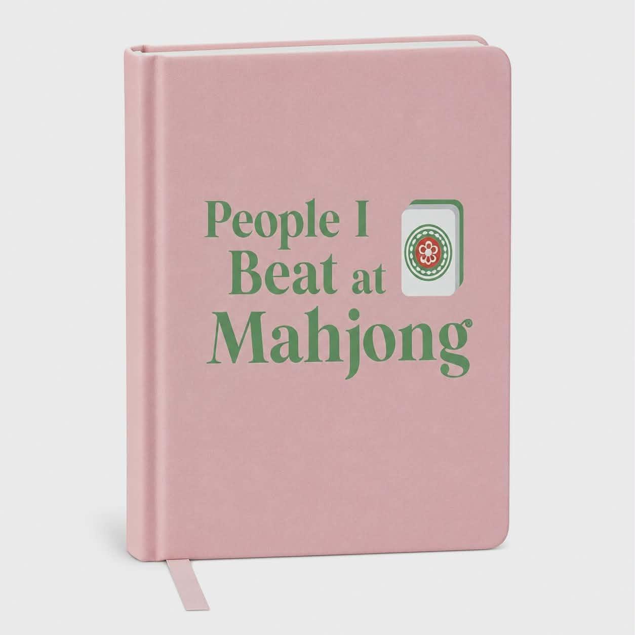 Blush pink hardcover blank journal with the phrase "People I Beat at Mahjong®" and a Mahjong tile illustration.