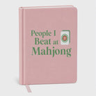 Blush pink hardcover blank journal with the phrase "People I Beat at Mahjong®" and a Mahjong tile illustration.