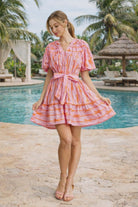 Bubble pink bow print mini dress with puff sleeves and tie waist styled in a tropical resort setting