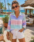 Woman wearing pastel striped seersucker blouse by Orly styled with white shorts in a tropical resort setting