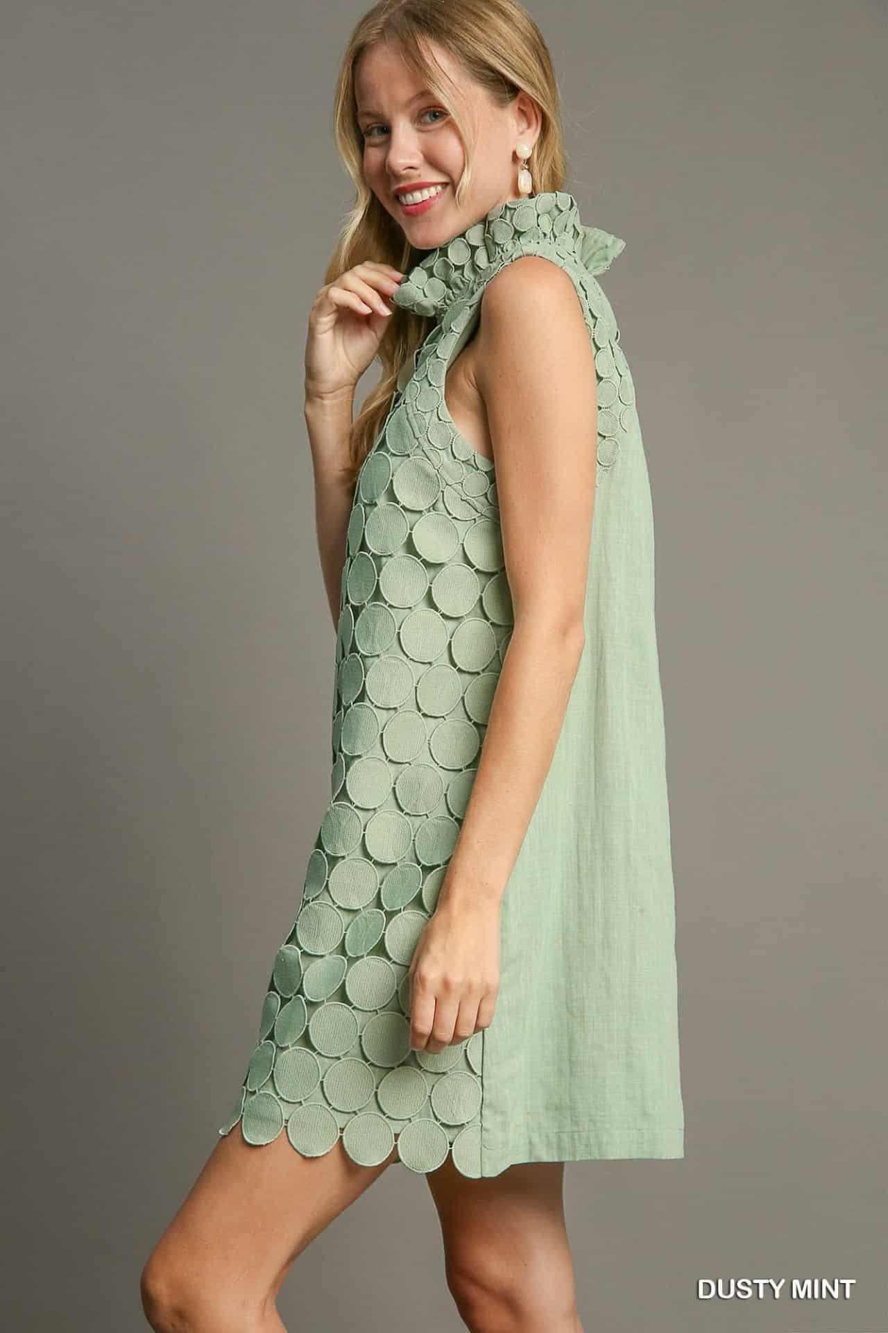 Woman wearing a light green dress with a textured pattern on a gray , side viewbackground