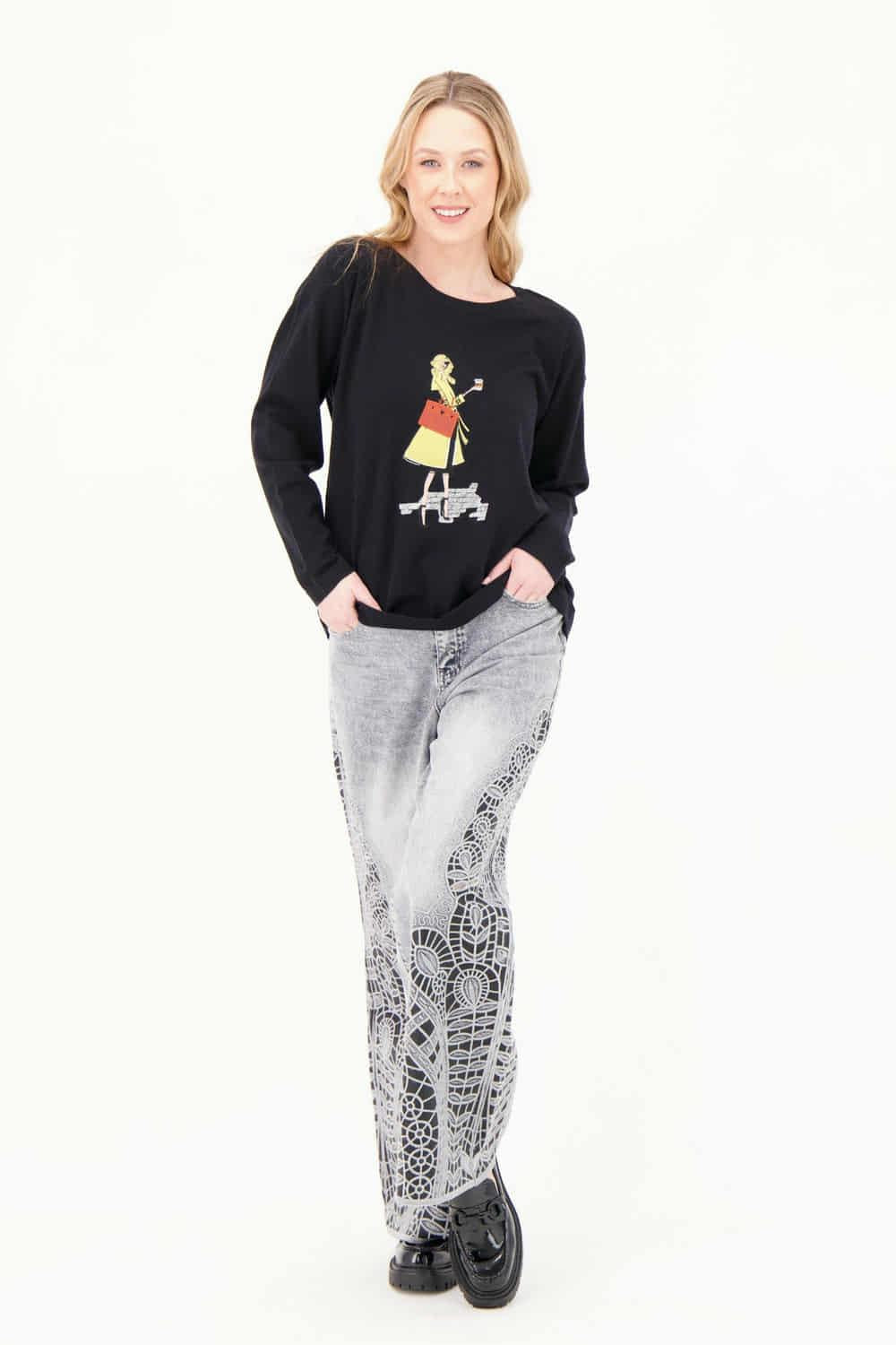 Model wearing Gabby Isabella black sweater featuring a colorful fashion-girl graphic with a yellow coat and red handbag,  WHITE BACKGROUND— Petunias of Naples